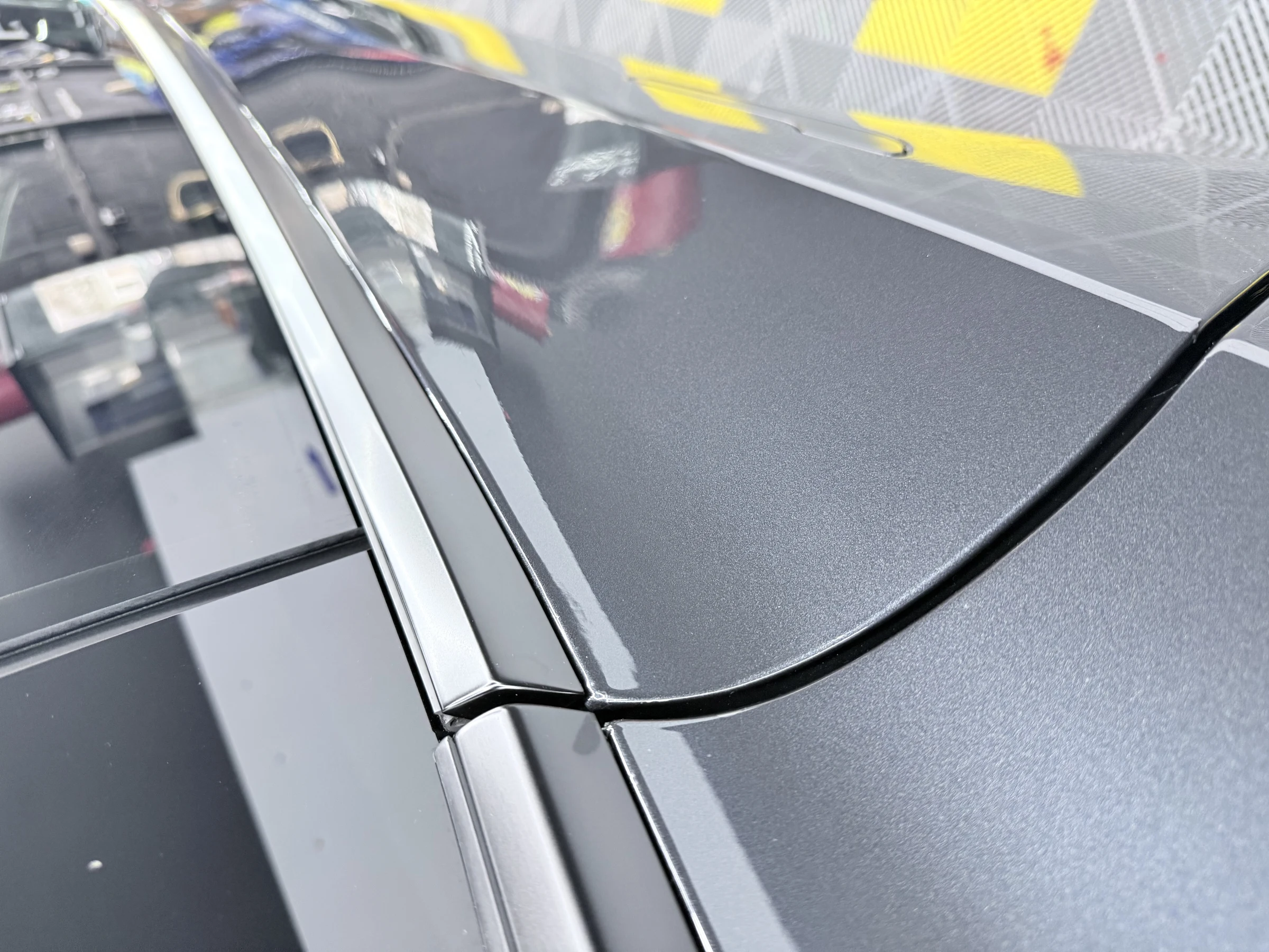 Close-up of the protected roof trim and paint finish on a black Tesla Model Y