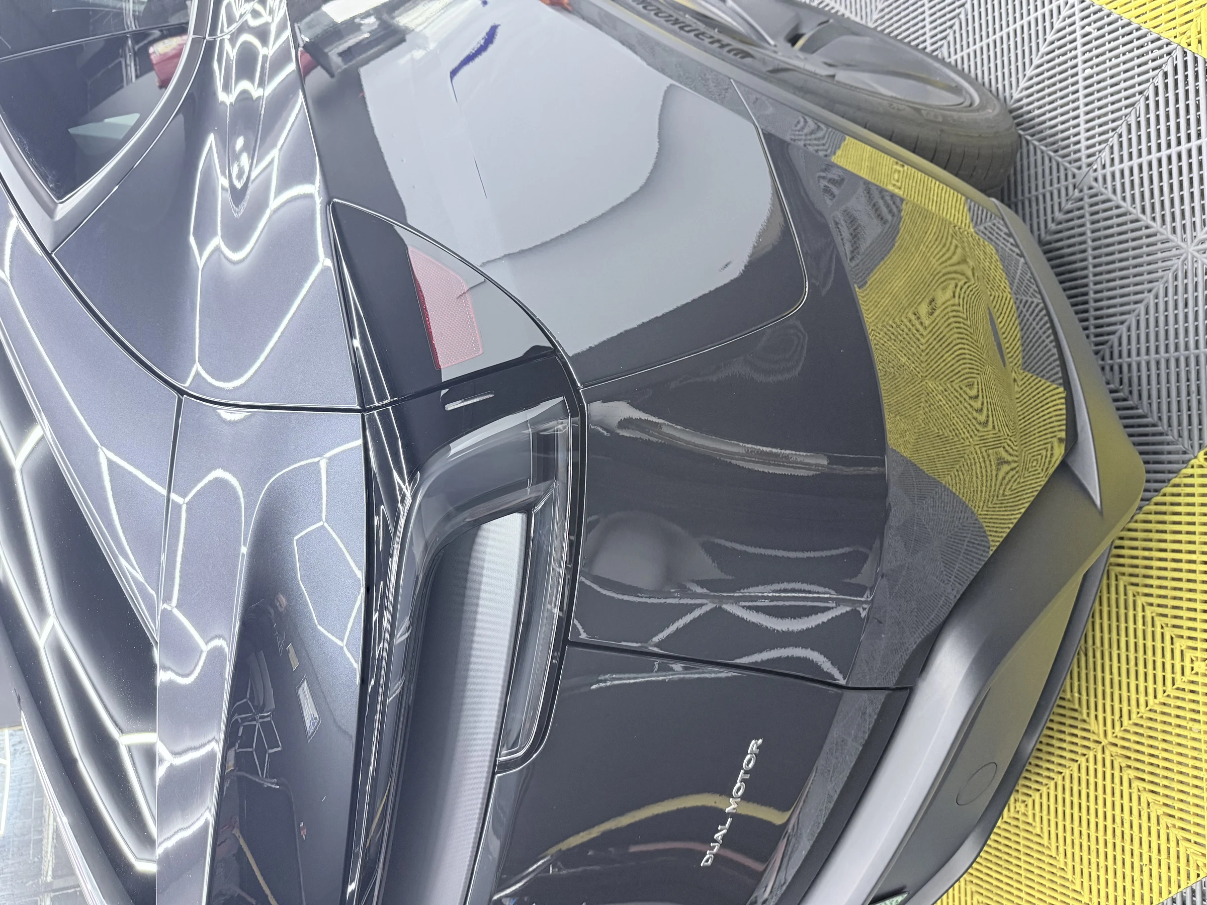 Close-up of the finished rear paint protection film coverage on a black Tesla Model Y