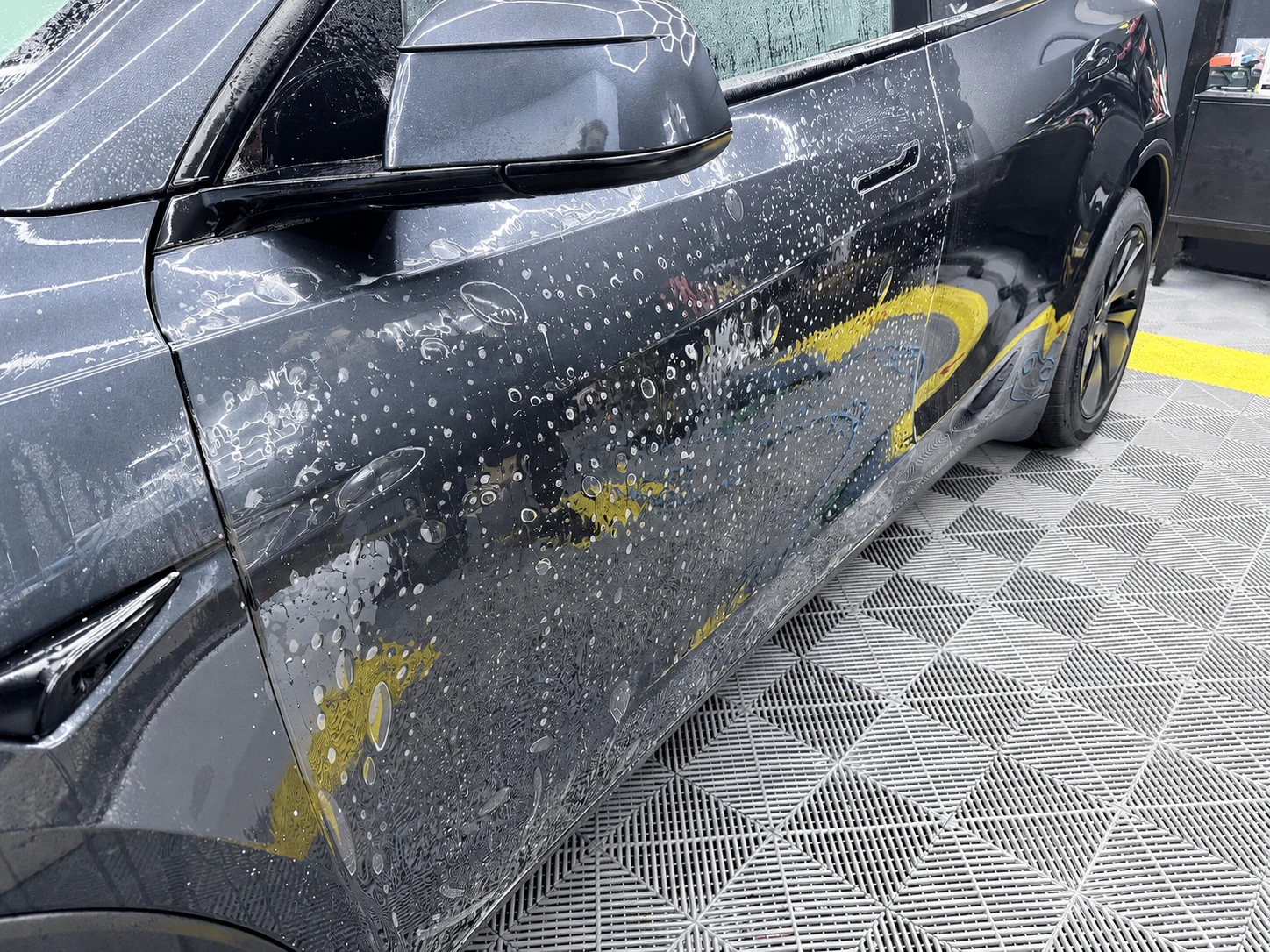 Paint protection film being installed on the side doors of a black Tesla Model Y